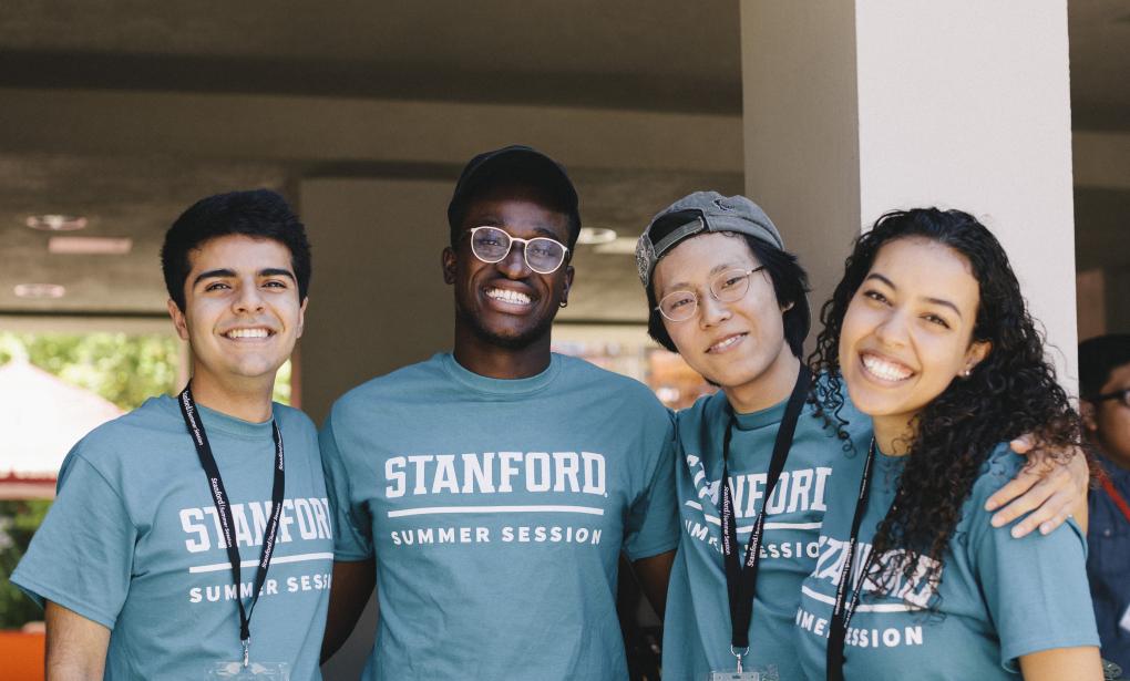 Four student staff members smile at the camera with their arms around each other.